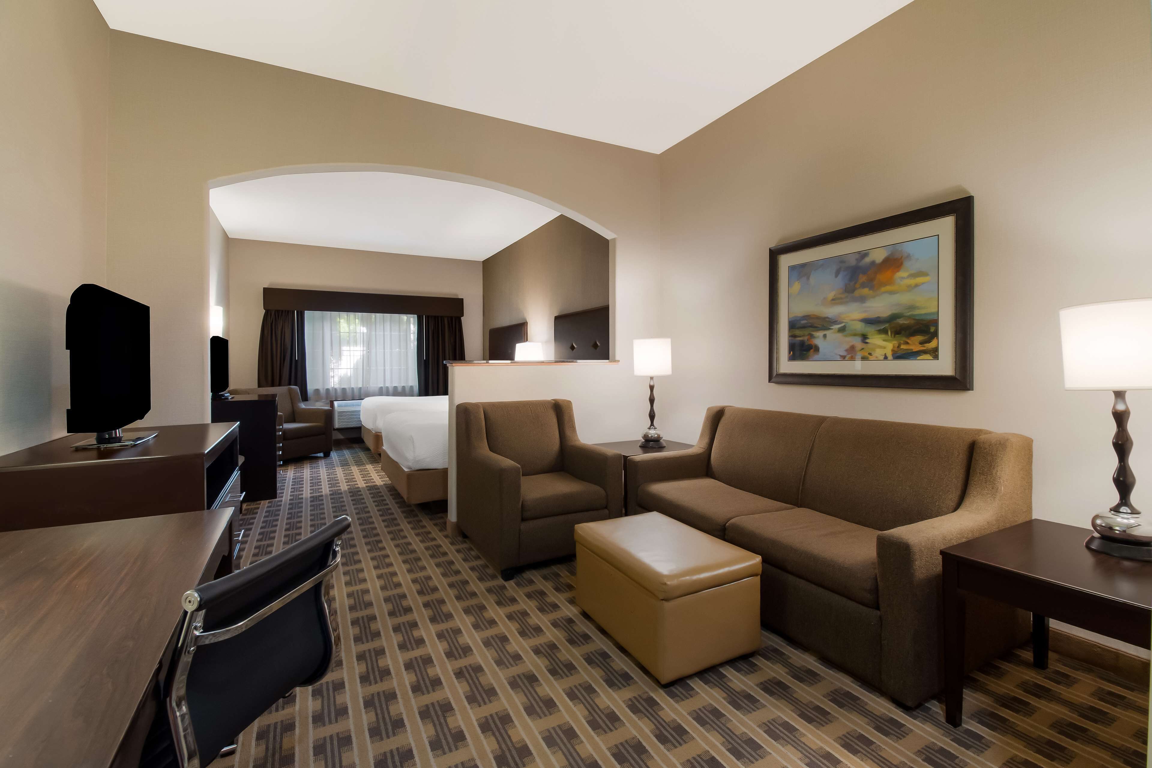 A hotel room with a bed, two sofas, a coffee table, a TV, and a desk.