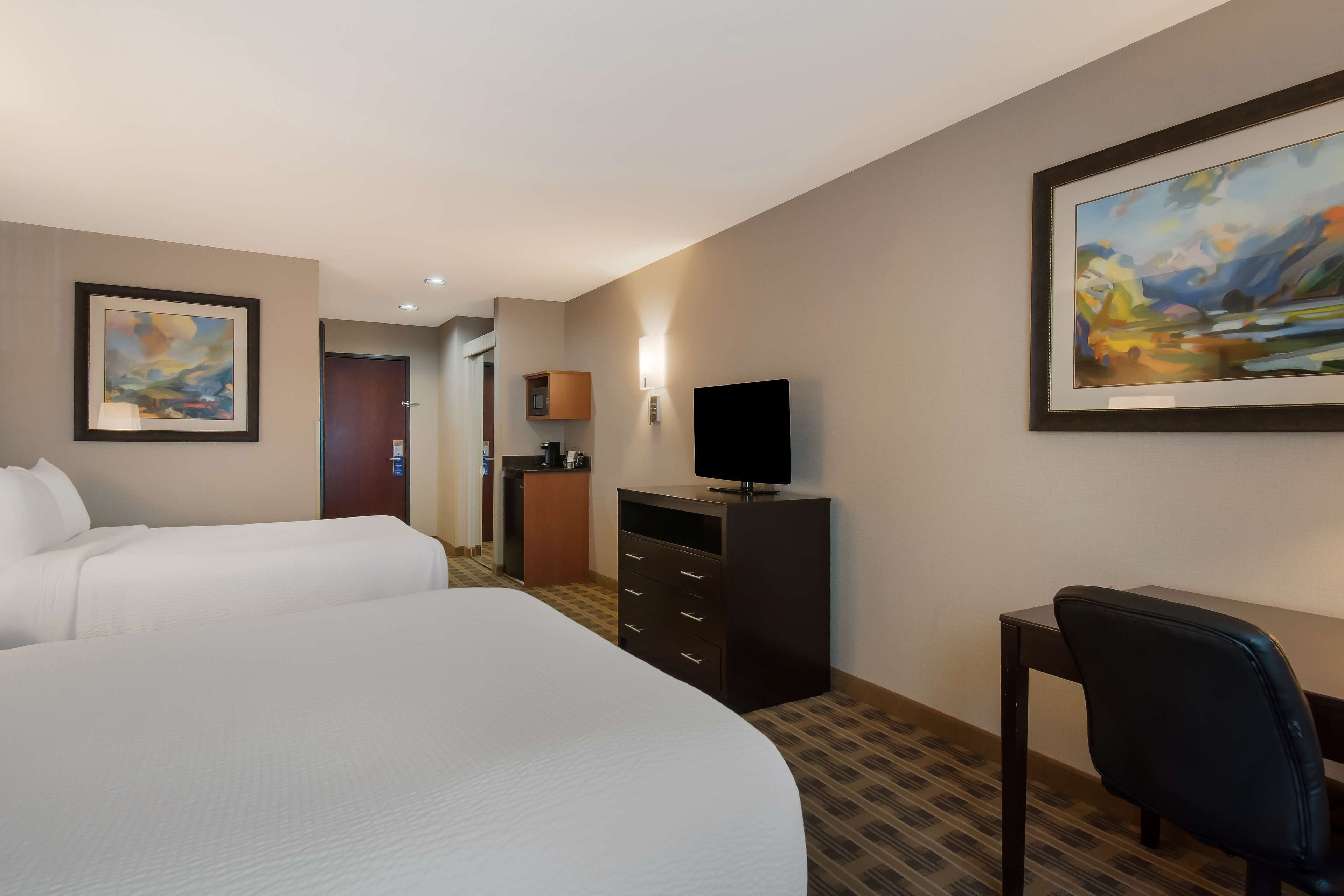 Habitación de hotel con dos camas, televisión, escritorio y cómoda.