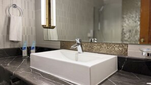 Une salle de bain avec un lavabo blanc, un robinet chromé et un miroir au-dessus.