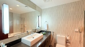 A modern bathroom with a large mirror, a sink, a toilet, and a shower. - Excelsior Hotel Downtown (Dubai)
