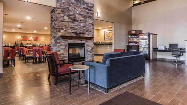 A spacious lobby with a stone fireplace, seating area, dining area, and a kitchenette. - Comfort Suites Fort Wayne North (Fort Wayne)