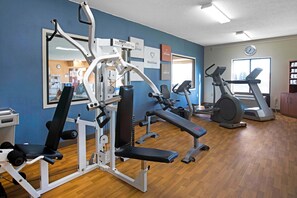 Une salle de sport équipée de matériel d’exercice, d’un tapis de course et d’un miroir.