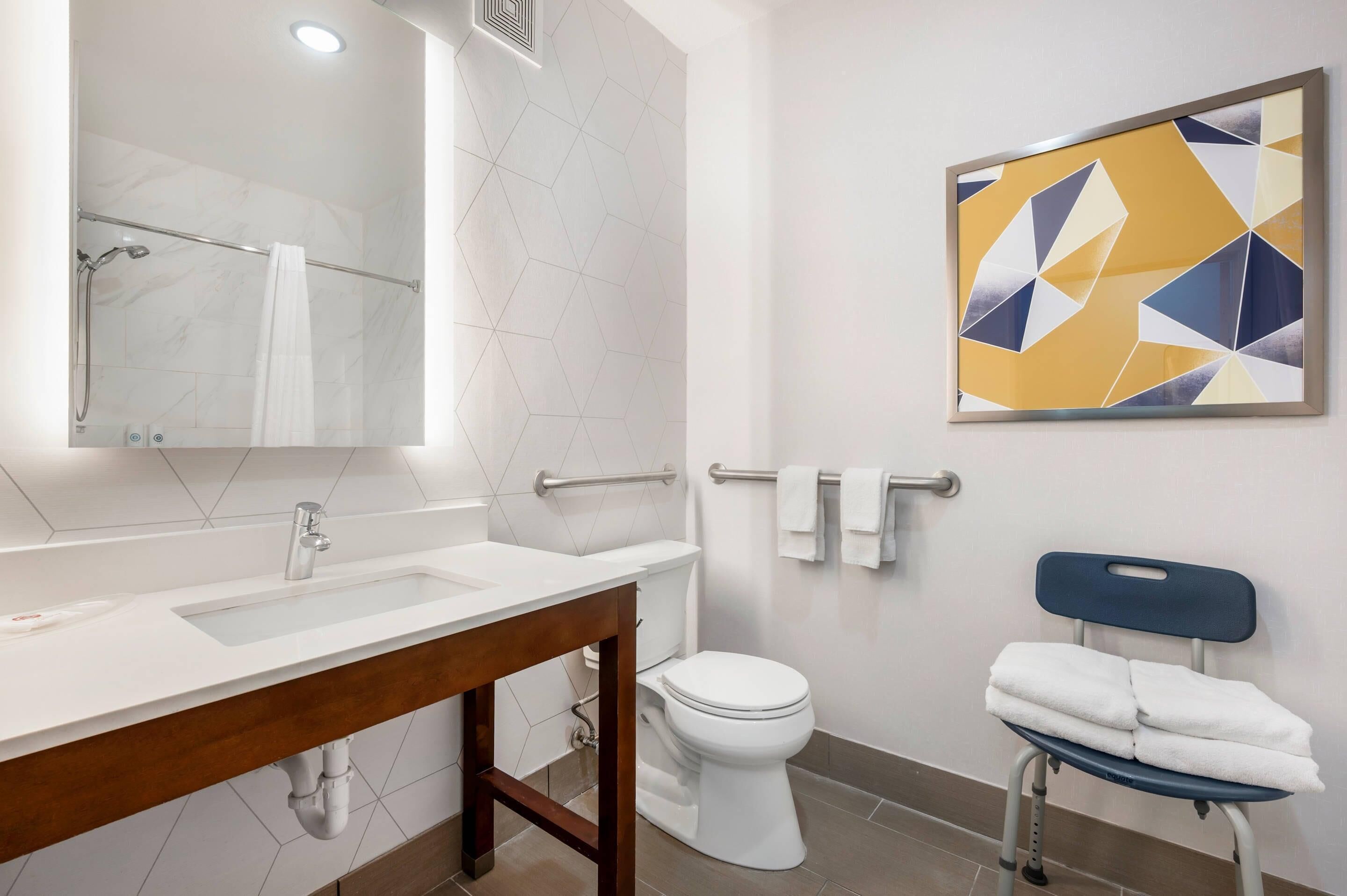 A bathroom with a white sink, mirror, toilet, and a towel rack.