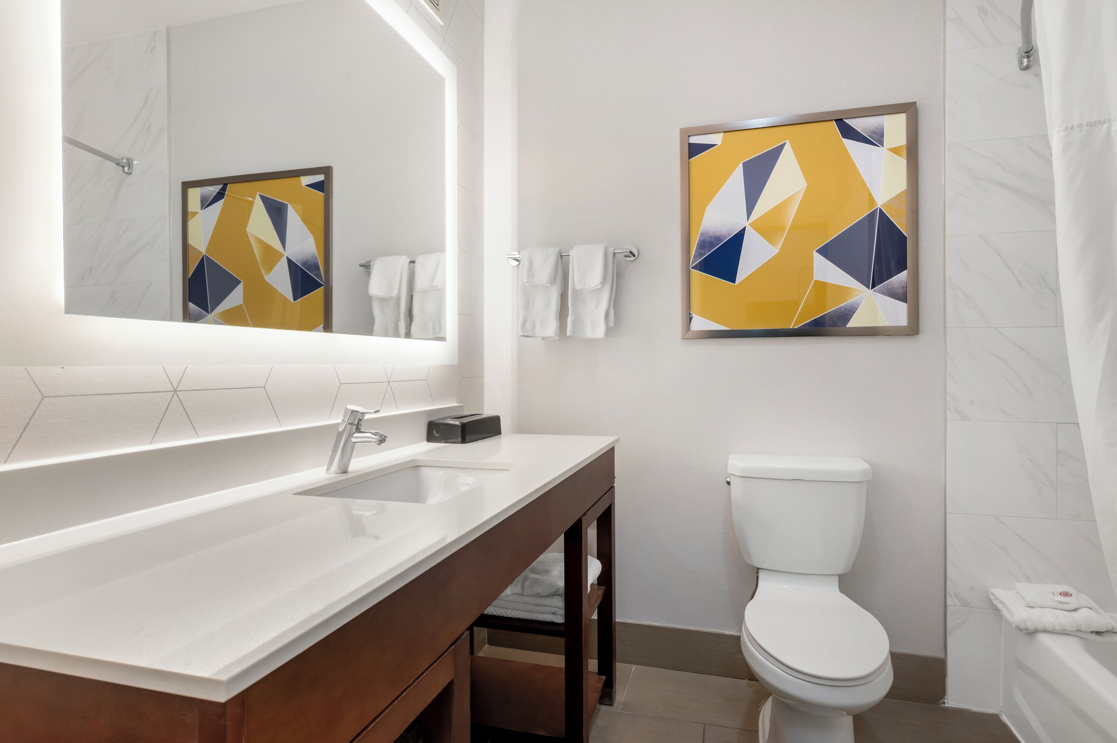 Une salle de bain moderne avec un grand miroir, un lavabo blanc, des toilettes et une baignoire.