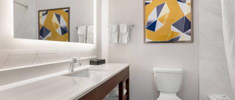 Un baño moderno con un espejo grande, un lavamanos blanco, un inodoro y una bañera.