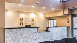 A reception area with a stone wall, a clock, and a sign for 'Comfort Suites'. - Comfort Suites Fort Wayne North (Fort Wayne)