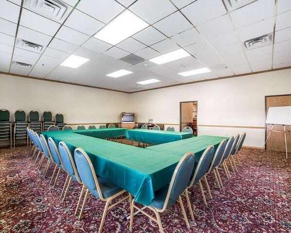 Un salón de conferencias con una larga mesa, sillas, una pizarra y suelo alfombrado.
