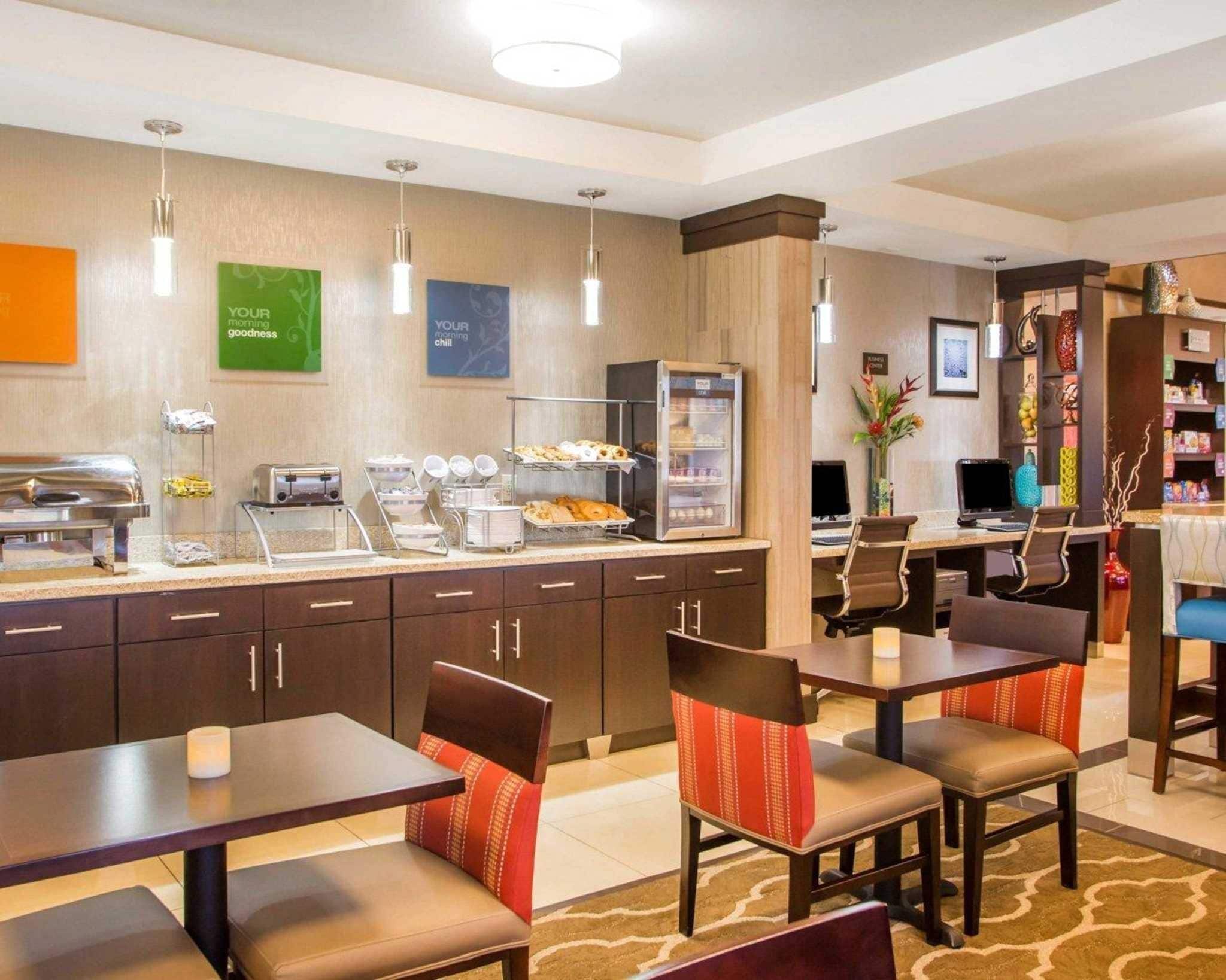 A hotel breakfast area with a buffet, seating, and a coffee station.