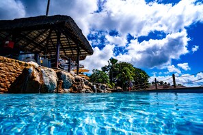 Una piscina al aire libre, sombrillas, sillones reclinables de piscina