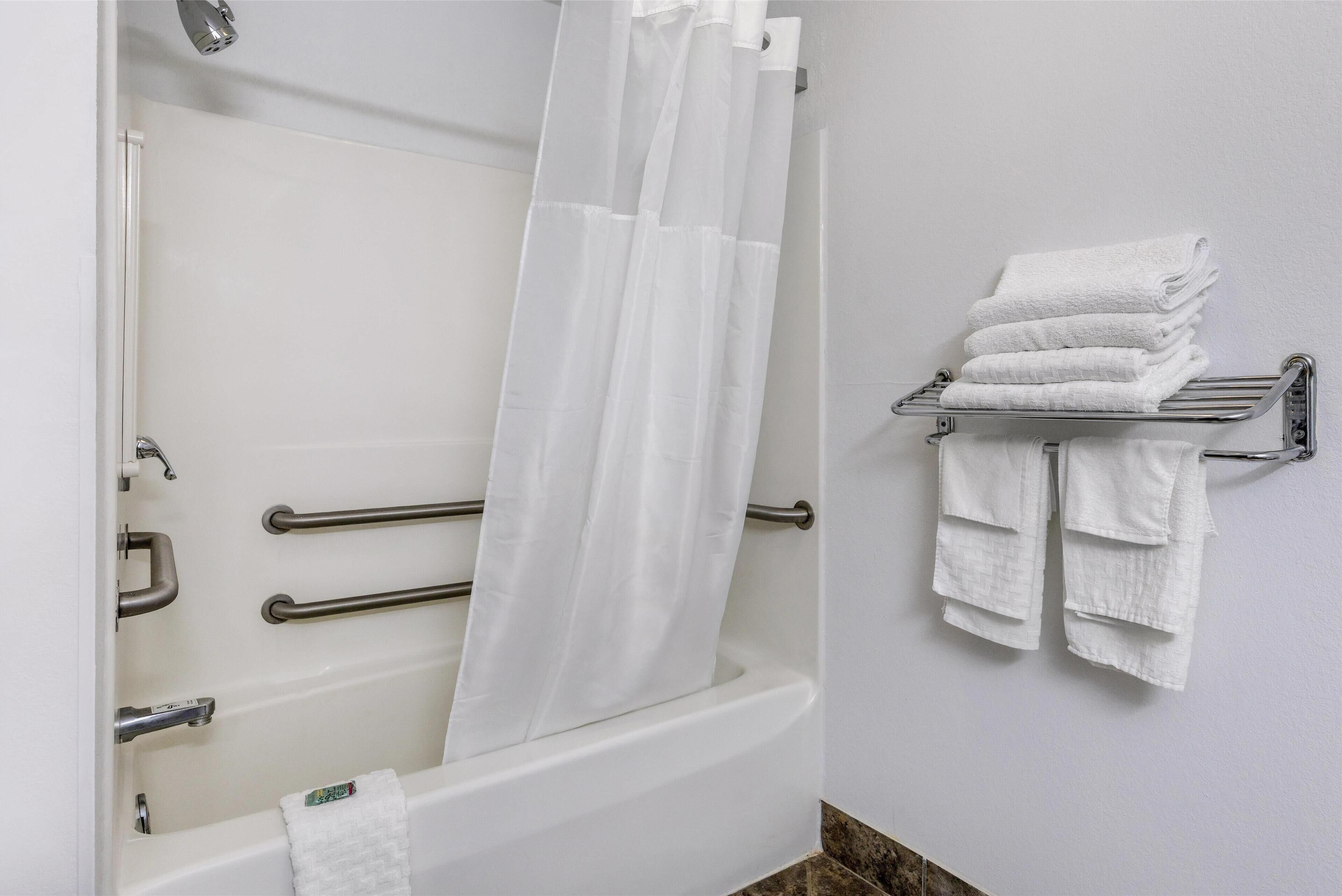 Un baño con bañera, cortina de ducha y un perchero con toallas dobladas.