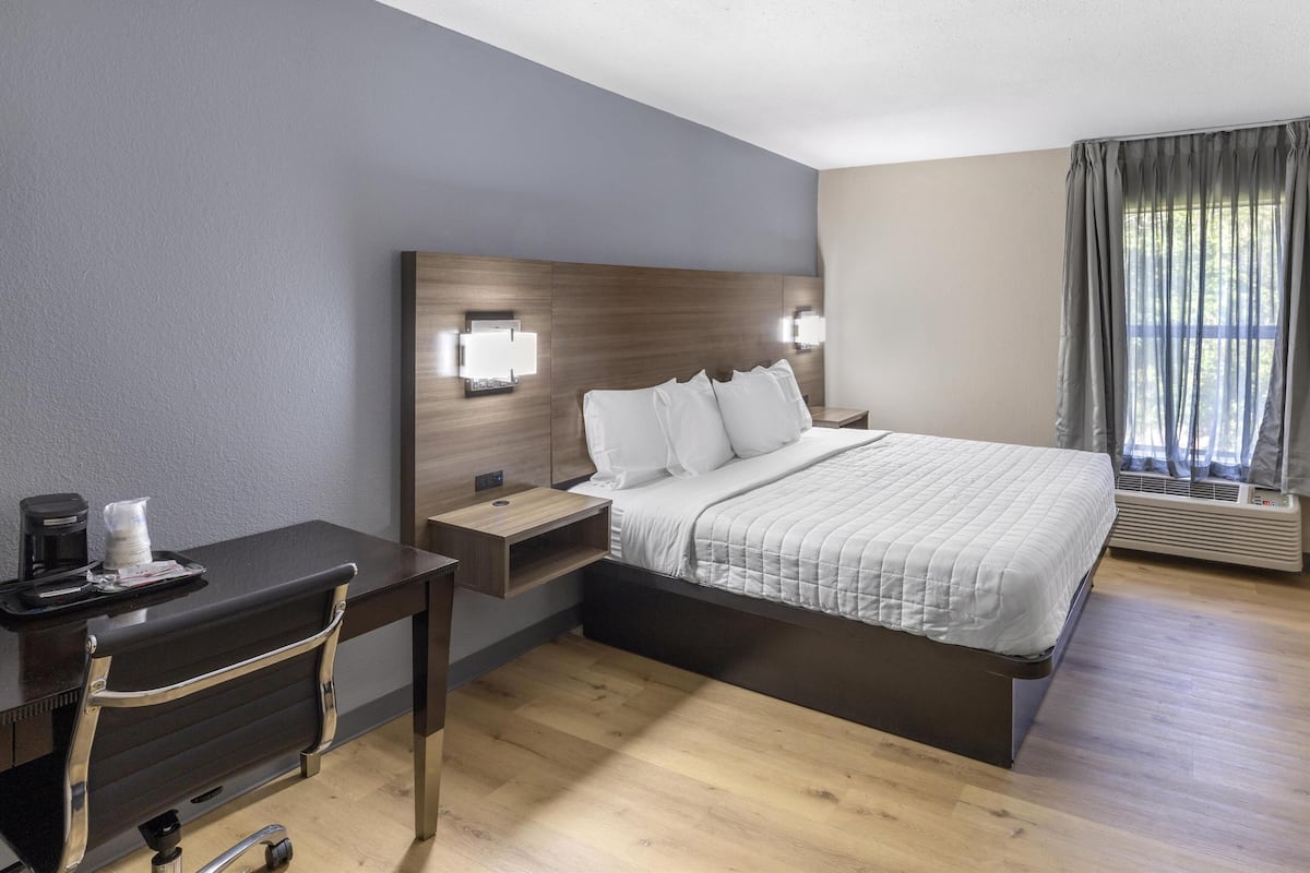 Ein Hotelzimmer mit einem Bett, Nachttischen, einem Schreibtisch und einem Sessel.