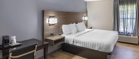 A hotel room with a bed, bedside tables, a desk, and a chair.