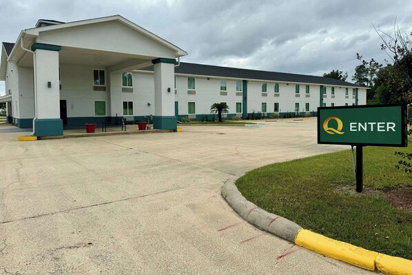 A hotel with a covered entrance, a sign reading "ENTER", and a parking lot.