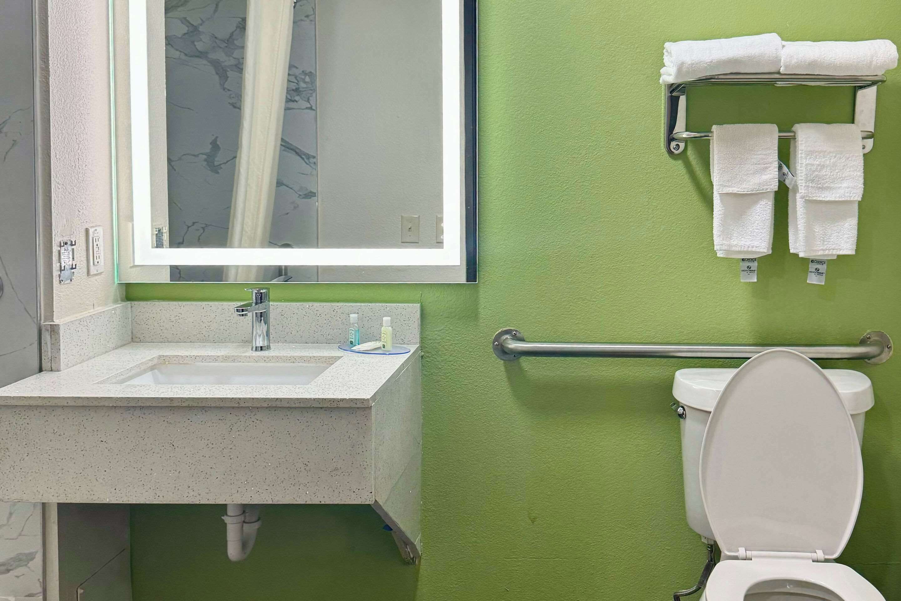 Un baño con lavamanos, espejo e inodoro.
