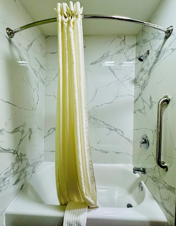 Un baño con cabina de ducha, bañera y paredes con diseño de mármol.