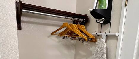 A small laundry area with a drying rack, a towel rack, and a hanging iron.