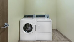 Una sala de bugaderia amb dues rentadores blanques i una porta.