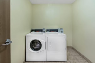 Un lavadero con dos lavadoras blancas y una puerta.