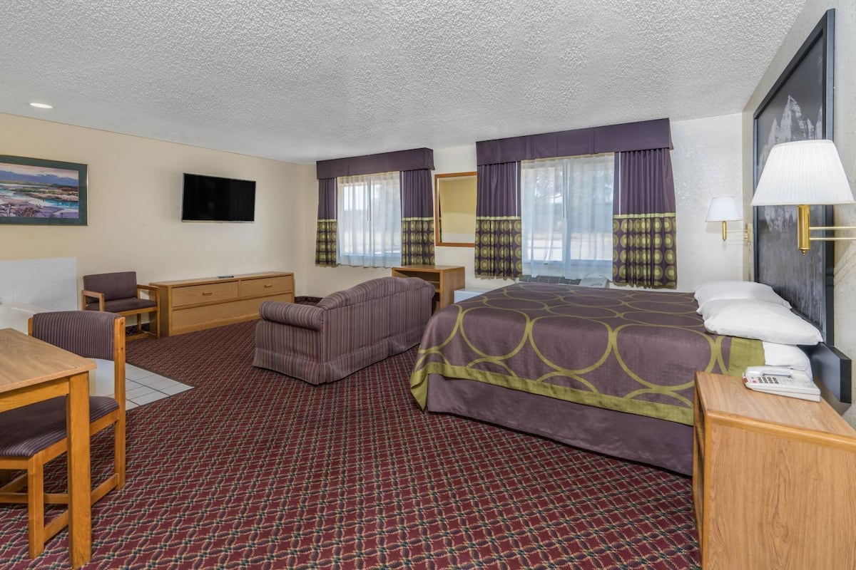 A hotel room with a bed, a sofa, a desk, and a television.