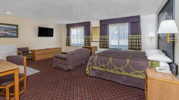 A hotel room with a bed, a sofa, a desk, a chair, a television, and a window with curtains.