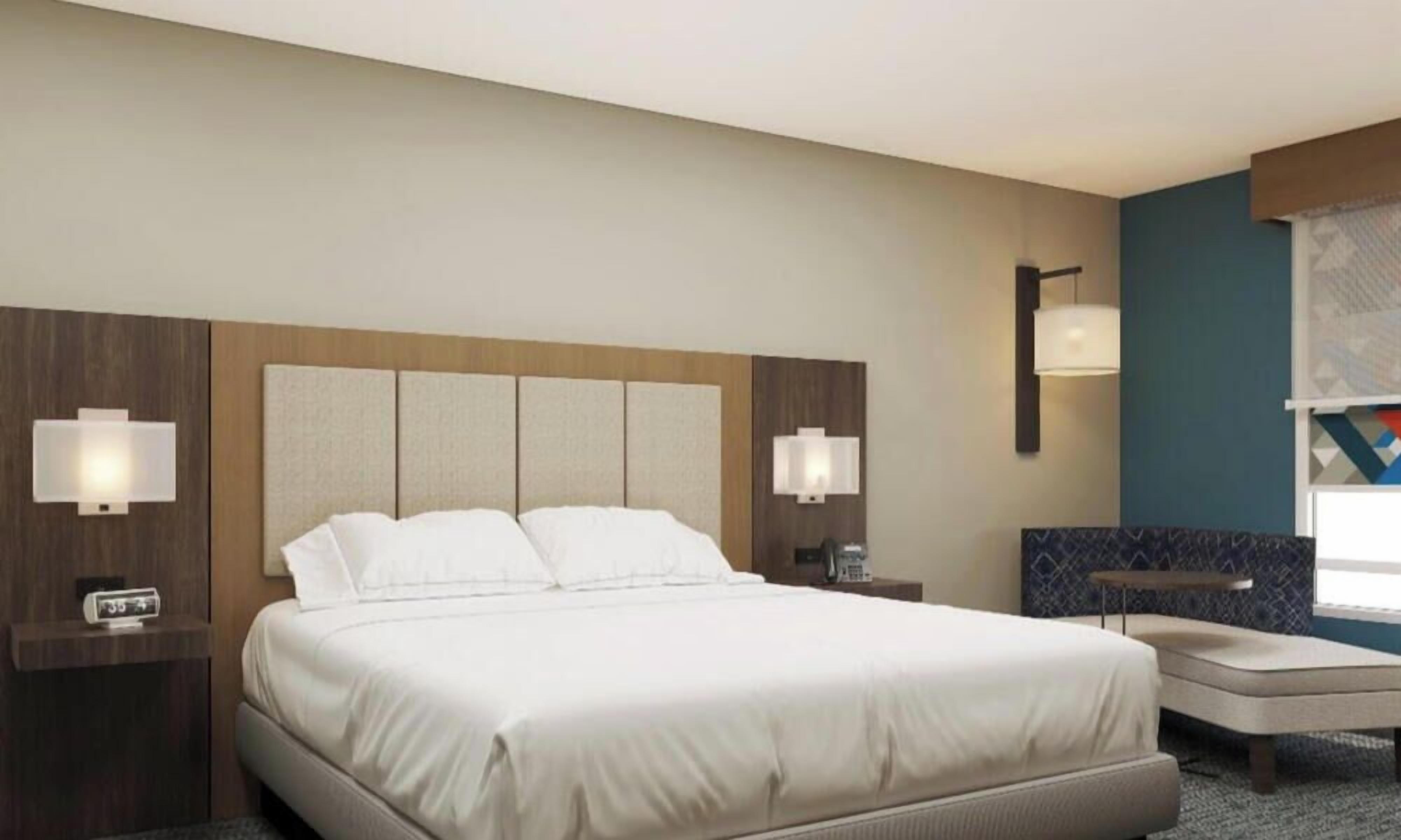 Una habitación de hotel con una cama grande, mesitas de noche, un escritorio y una silla.