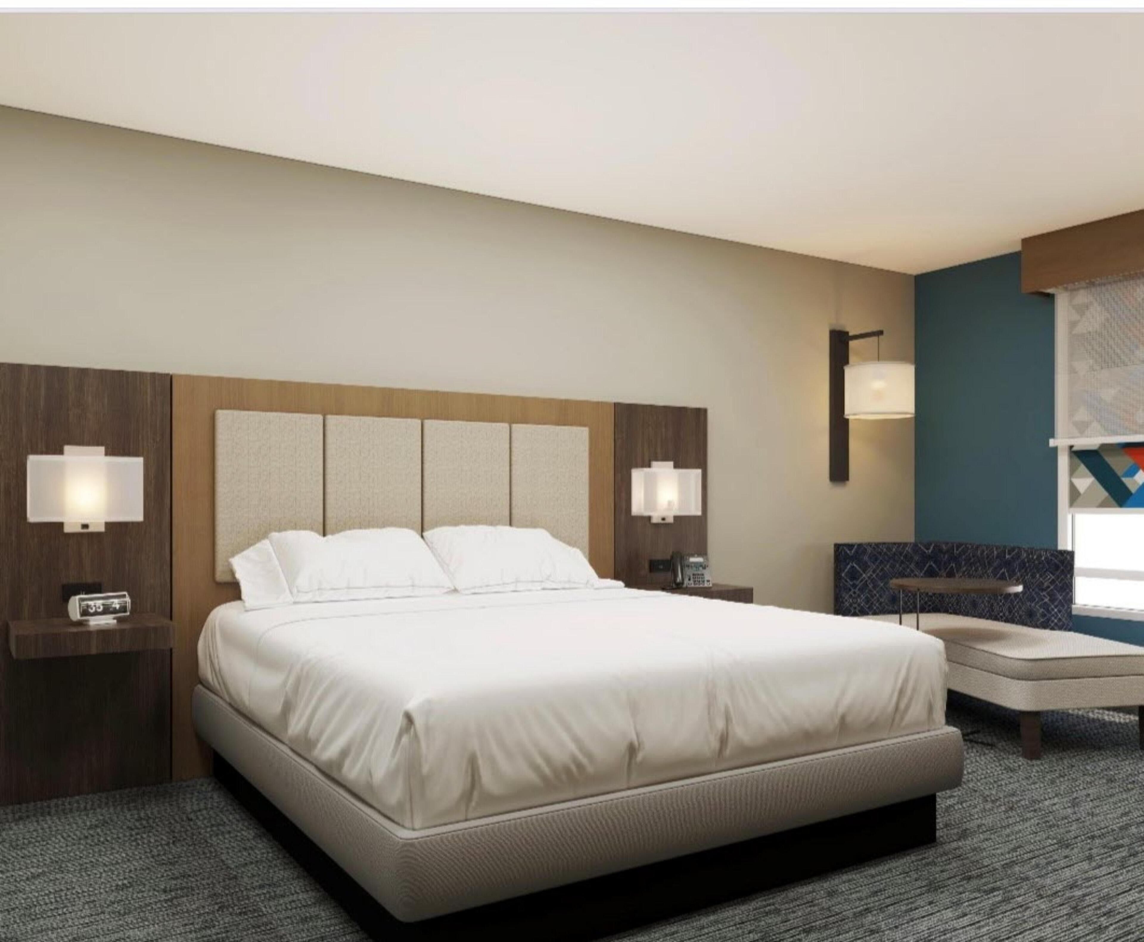 A hotel room with a large bed, bedside lamps, a desk, and a chair.