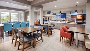 A modern dining area with wooden tables and chairs, a bakery counter, and a view of the outdoors. - Holiday Inn Express Redding North by IHG (Redding)