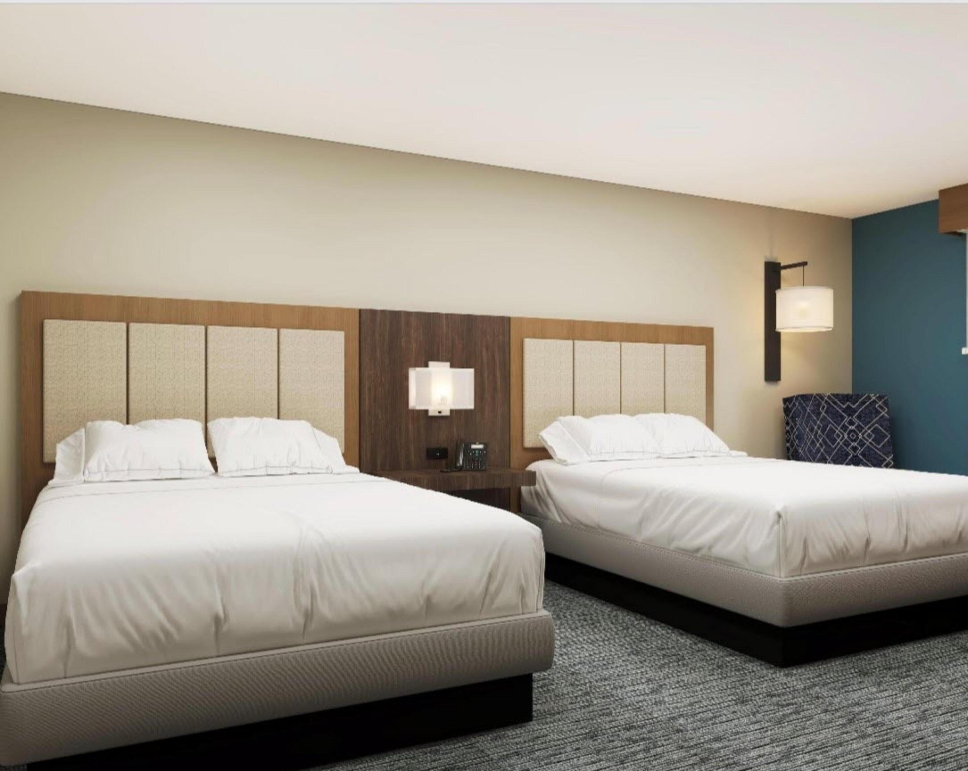 Two twin beds with headboards, a bedside table with a lamp, and a wall-mounted light fixture.