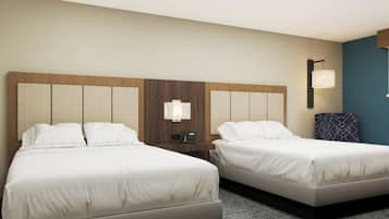 A hotel room with two beds, a nightstand with a lamp, and a blue accent wall.