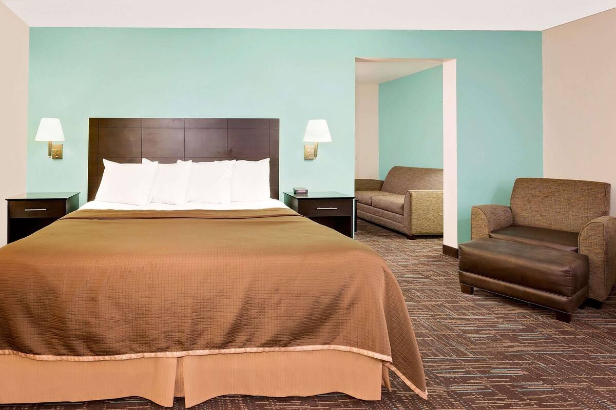 Een hotelkamer met een groot bed, twee nachtkastjes, een stoel en een bank.