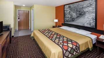 A hotel room with a bed, a desk, a chair, a lamp, a telephone, and a painting on the wall.