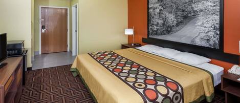 A hotel room with a bed, a desk, a chair, a lamp, a telephone, and a painting on the wall.