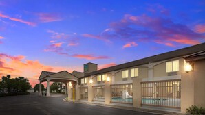 A hotel with a pool, a covered parking area, and a sunset sky.