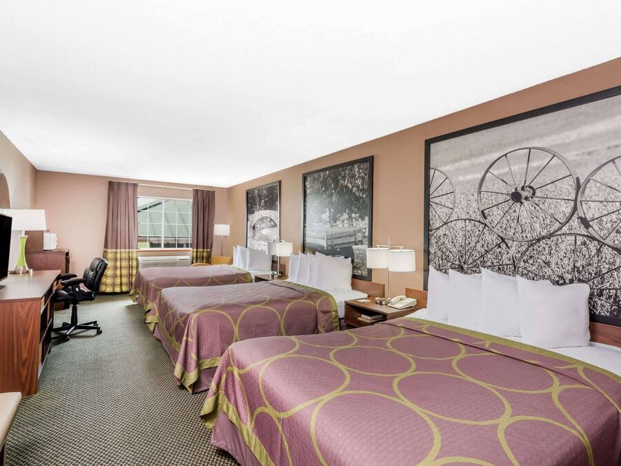 A hotel room with two beds, a desk with a chair, a television, and a large window.