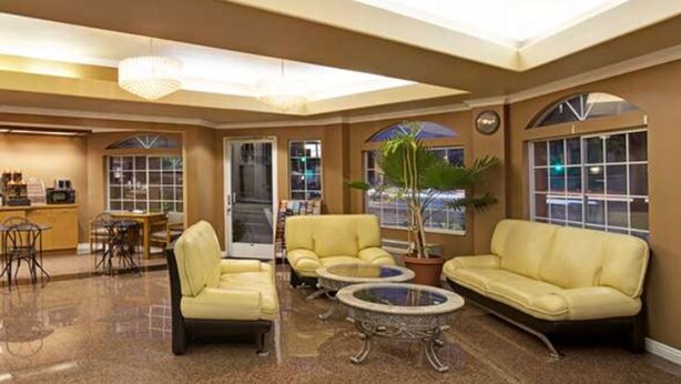 A spacious lobby with a high ceiling, a chandelier, a reception desk, and seating areas. - Super 8 by Wyndham Los Angeles Downtown (Los Angeles)