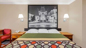 A hotel room with a bed, two bedside tables, a chair, a large framed picture on the wall, and two wall-mounted lamps. - Super 8 by Wyndham Los Angeles Downtown (Los Angeles)