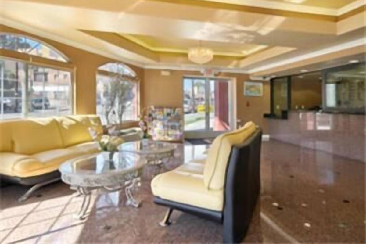 Een ruime lobby met een gele bank, een glazen salontafel en een kroonluchter.
