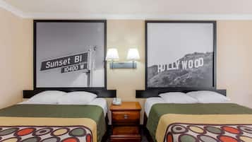 Ein Hotelzimmer mit zwei Betten, einem Nachttisch mit Lampe und zwei gerahmten Bildern an der Wand.