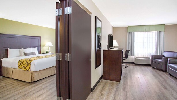 A hotel room with a bed, a desk, a chair, and a television. - Baymont by Wyndham Phoenix I-10 near 51st Ave (Phoenix)