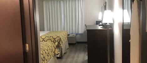 Una habitación de hotel con cama, escritorio, cómoda y espejo.
