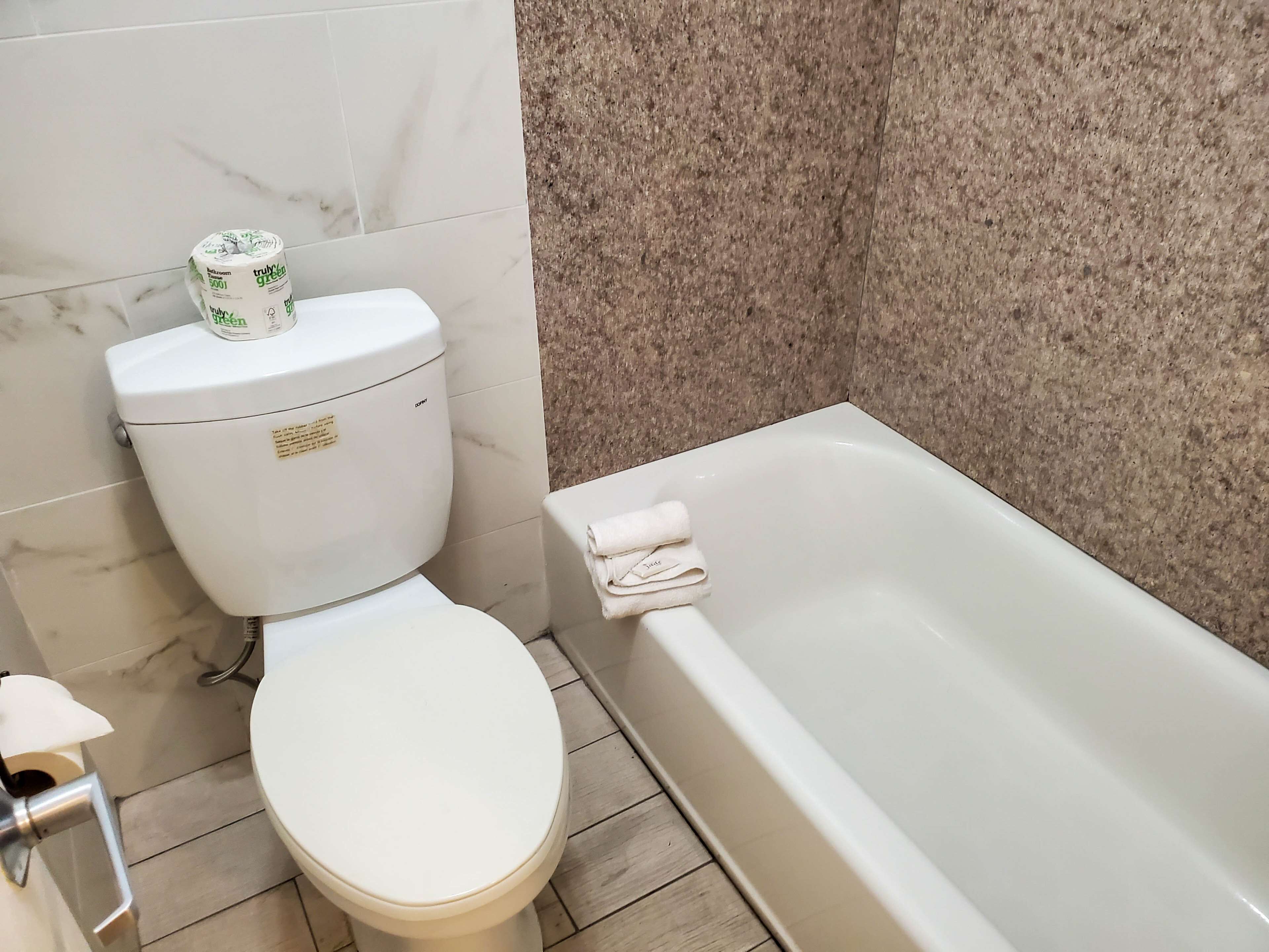 Une salle de bain équipée de toilettes, d’une baignoire et d’un mur recouvert de carreaux de marbre.