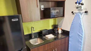 Cocina compacta equipada con refrigerador, microondas, lavaplatos y cafetera.
