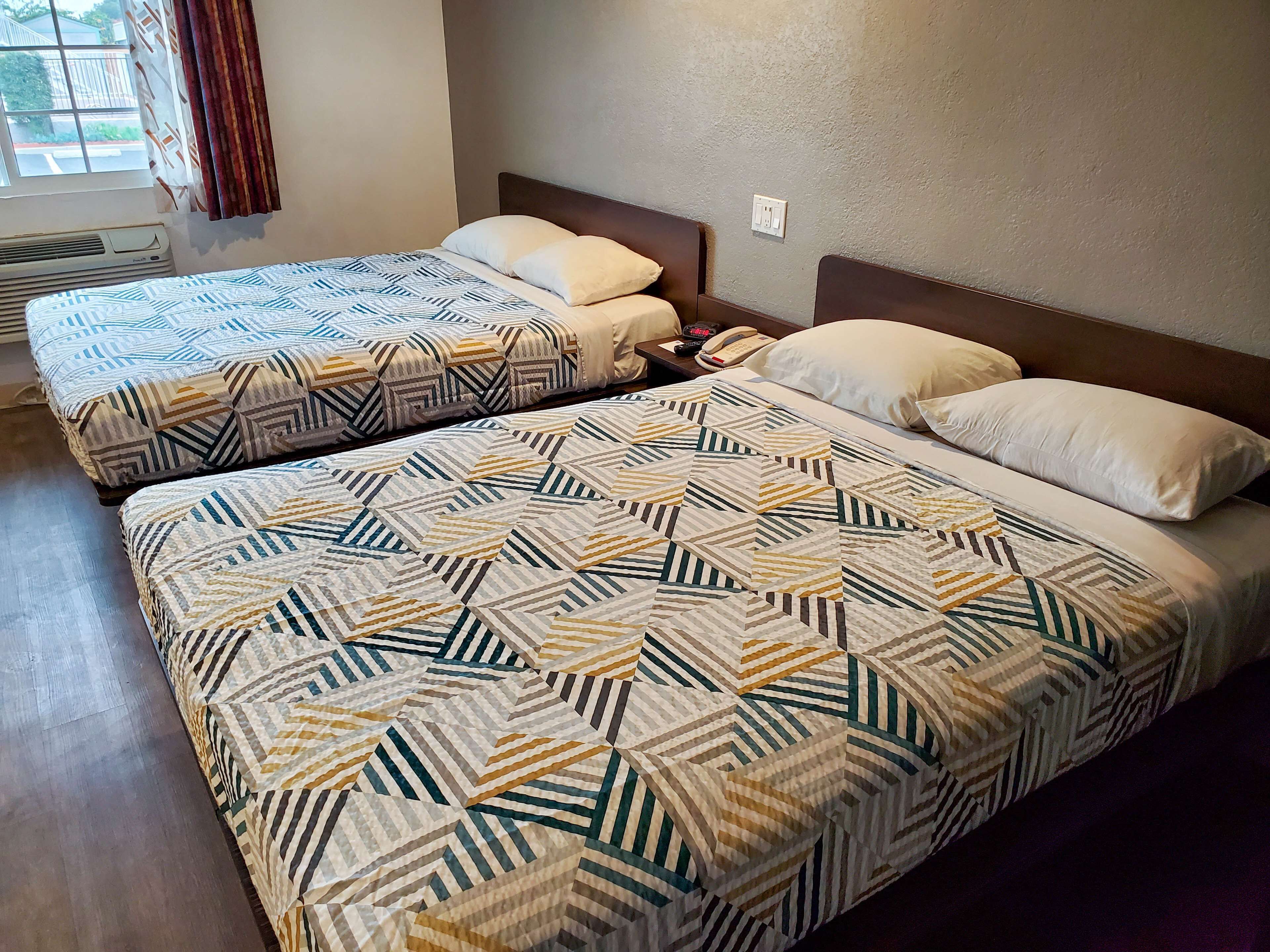 A hotel room with two beds, each with patterned bedding and a wooden headboard.