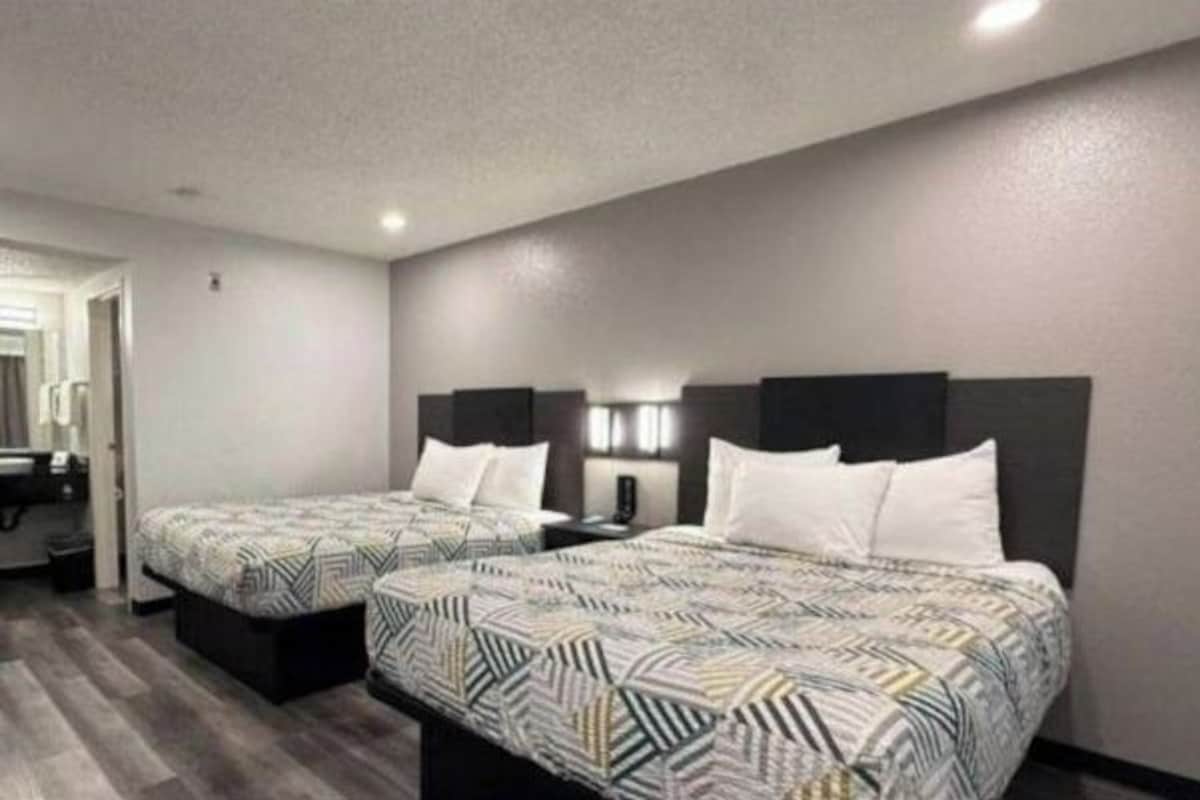 Habitación de hotel con dos camas, baño y un pequeño rincón de descanso.