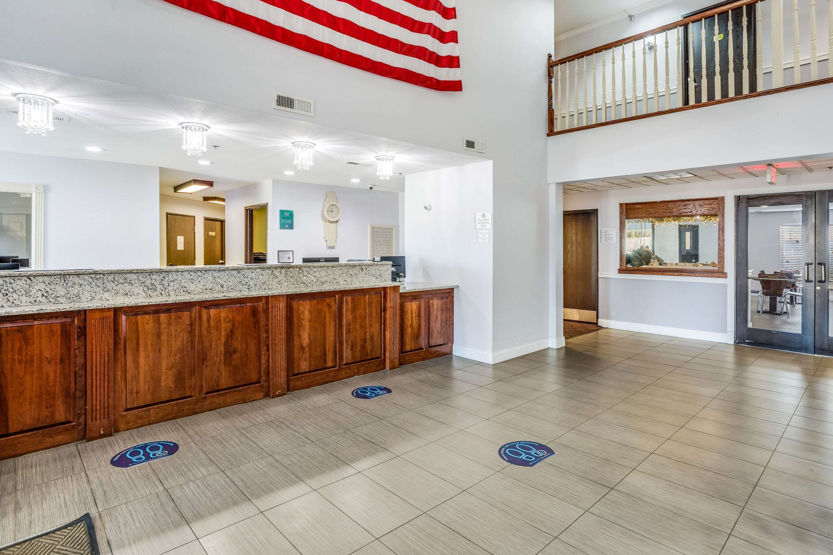 A hotel lobby with a reception desk, wooden paneling, a chandelier, and a large American flag.
