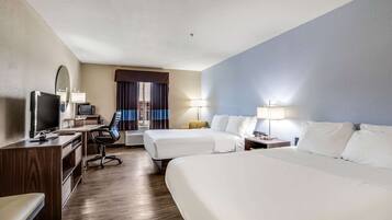 A hotel room with two beds, a desk with a computer, a TV, and a chair.