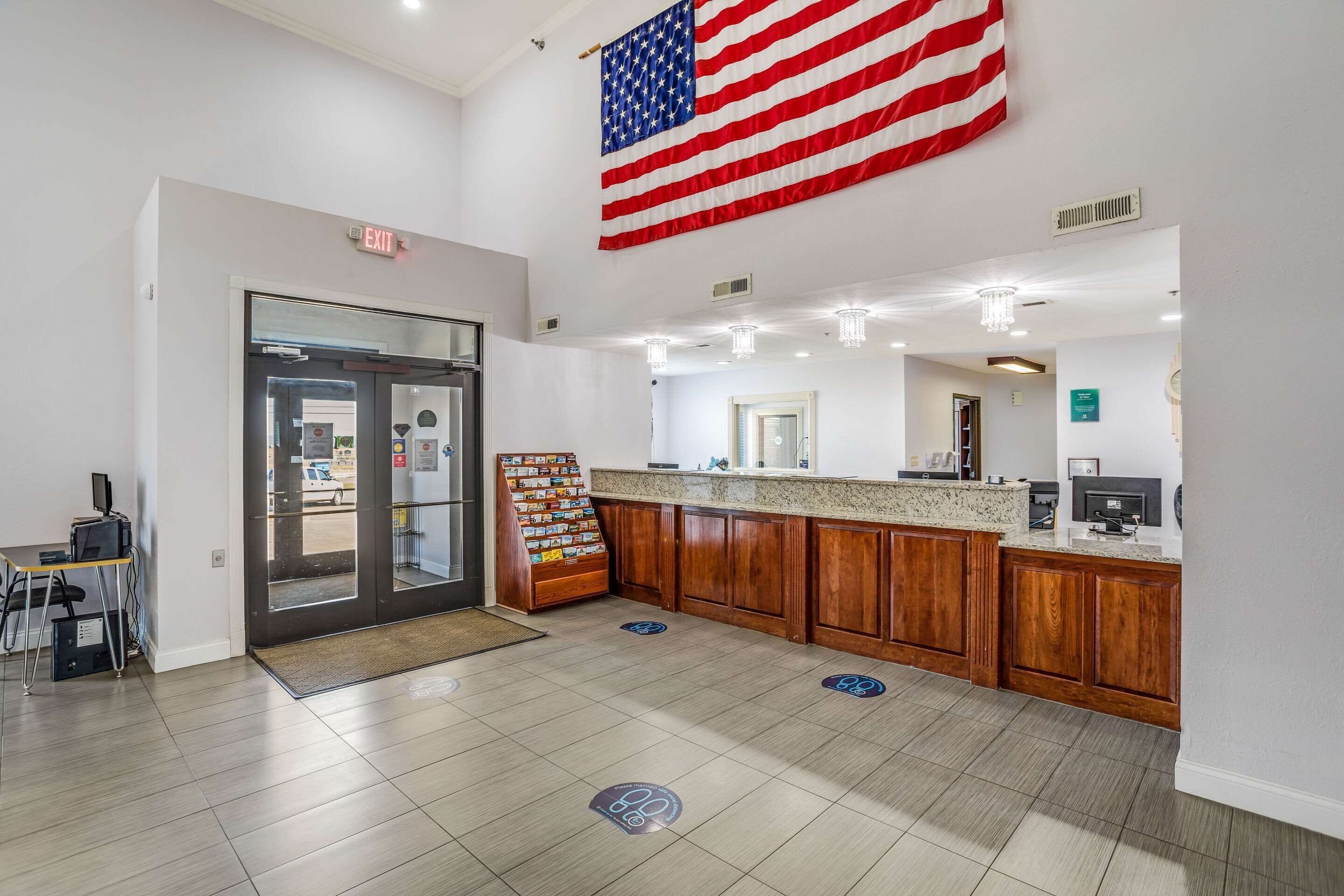 A lobby with a reception desk, a large American flag, and a counter with a menu board.