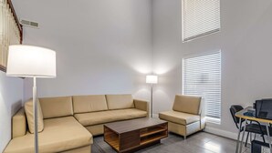 A modern living room with a sectional sofa, a coffee table, and a lamp.