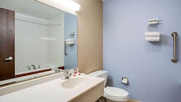 A bathroom with a white sink, mirror, and toilet. There is a towel rack with towels and a paper towel dispenser.