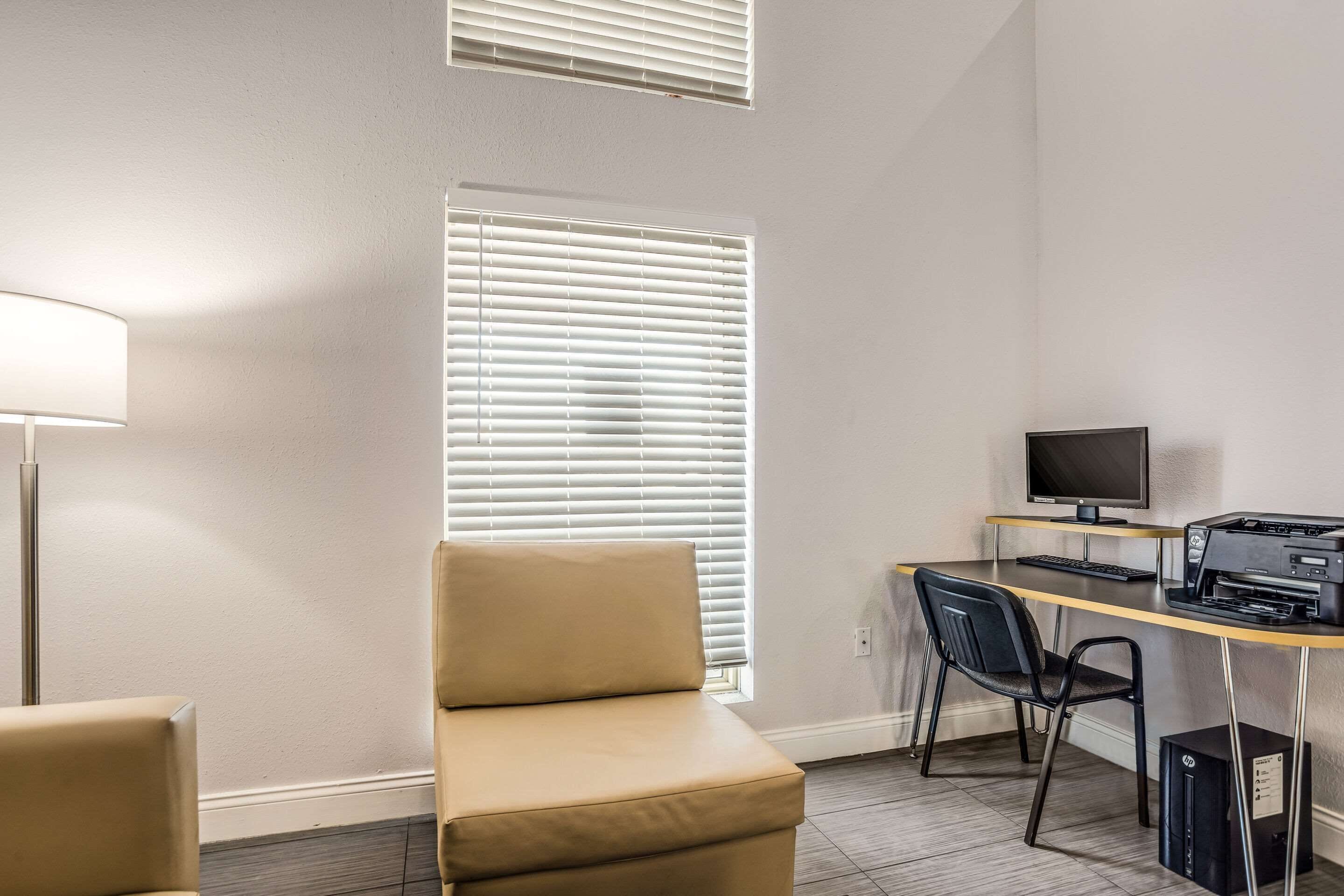 A room with a desk, computer, printer, and a chair.